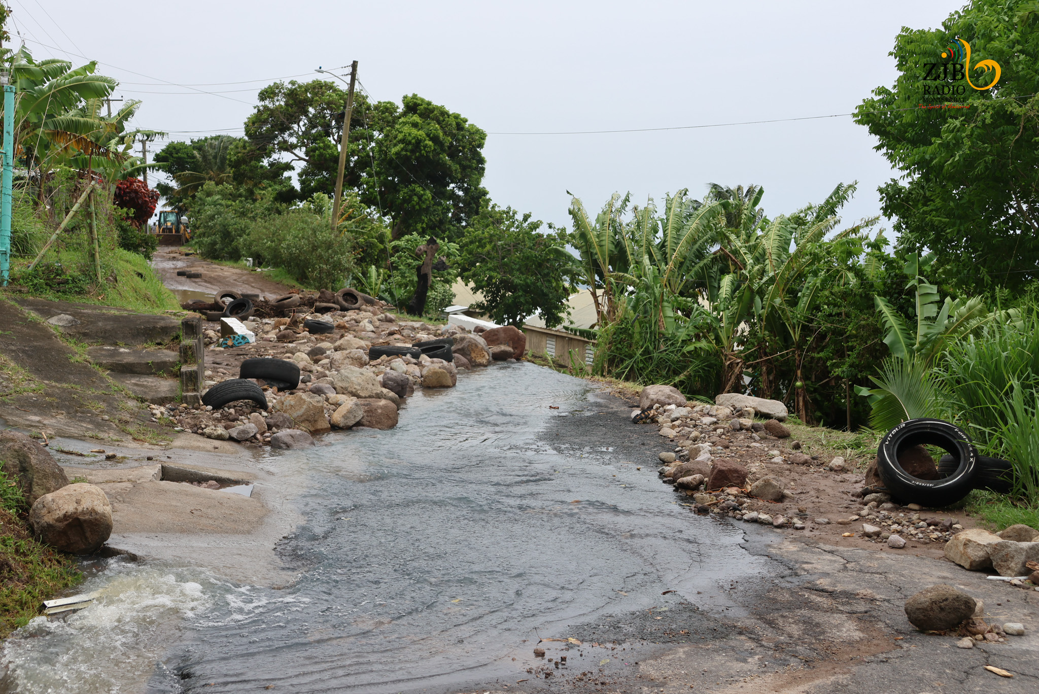 water running in the street with large boulders and other debris nearby