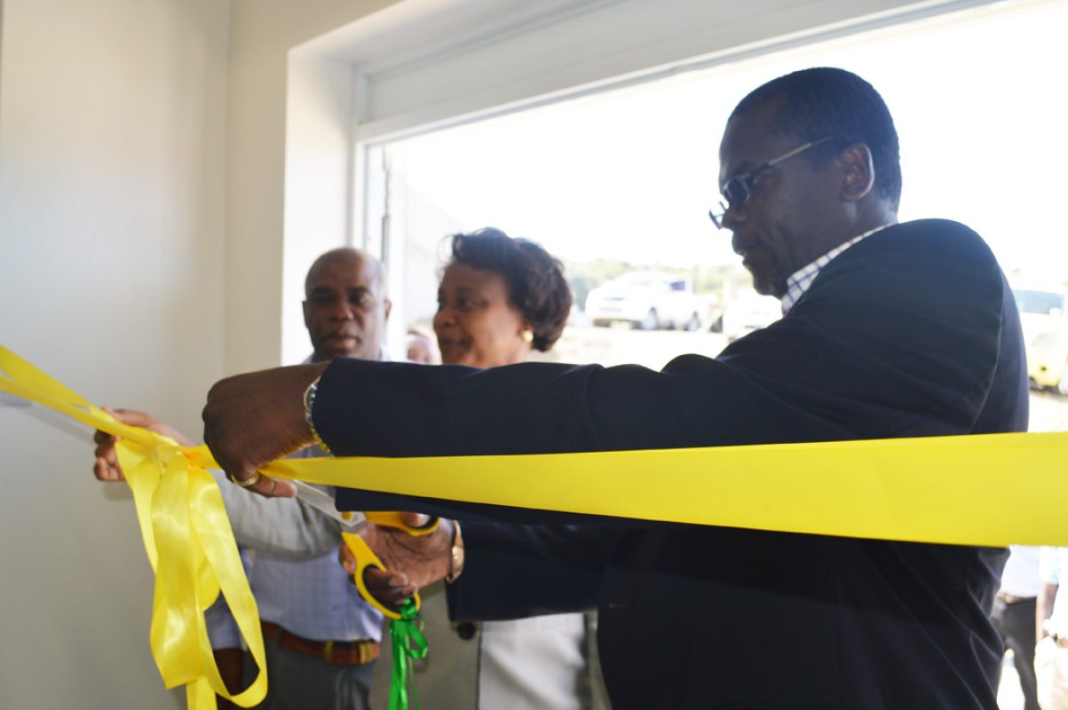 Minister of Agriculture Claude Hogan cuts the ribbon to officially open the abattoir while Permanent Secretary Daphne Cassell and Mervin Browne of BNTF look on.