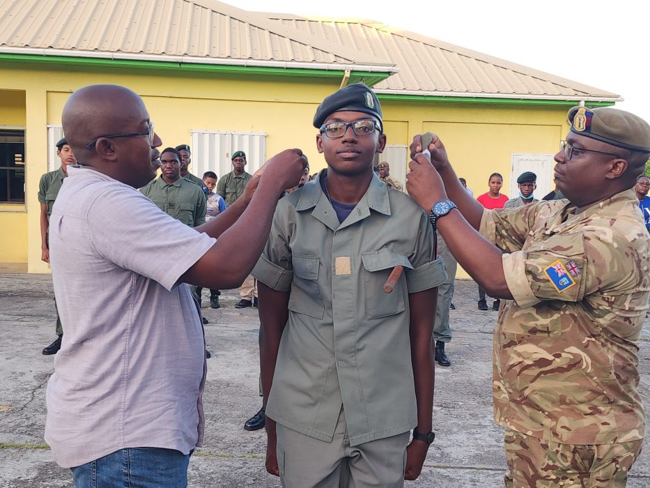 Montserrat's first Cadet Under Officer - Jeremiah Gilford receives his new insignias from his dad Police Sargeant George Gilford (left) and Colin Fergus (right)